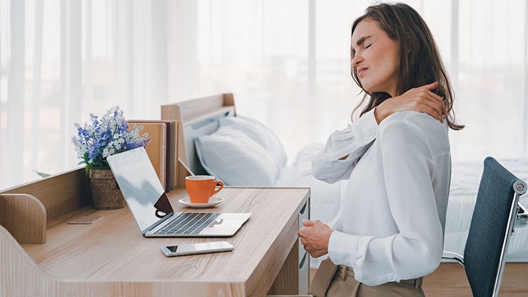 Frau hält sich im Homeoffice den Nacken Frau hält sich im Homeoffice den Nacken